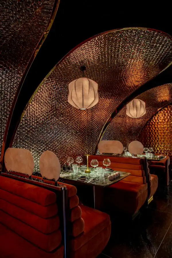 Vault of hammered copper, silk lanterns and red velvet banquettes