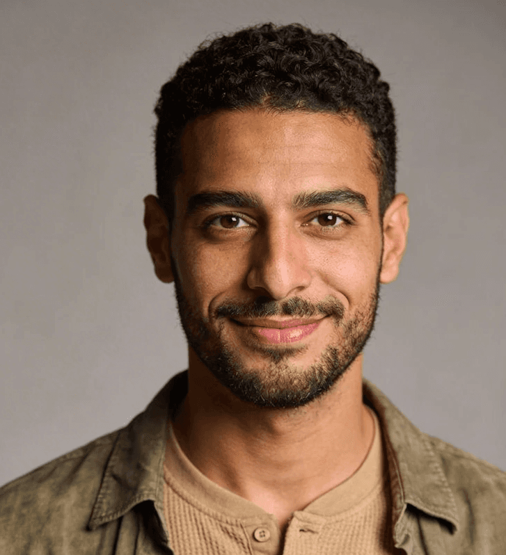 A potrait of a man looking towards camera on a plain background