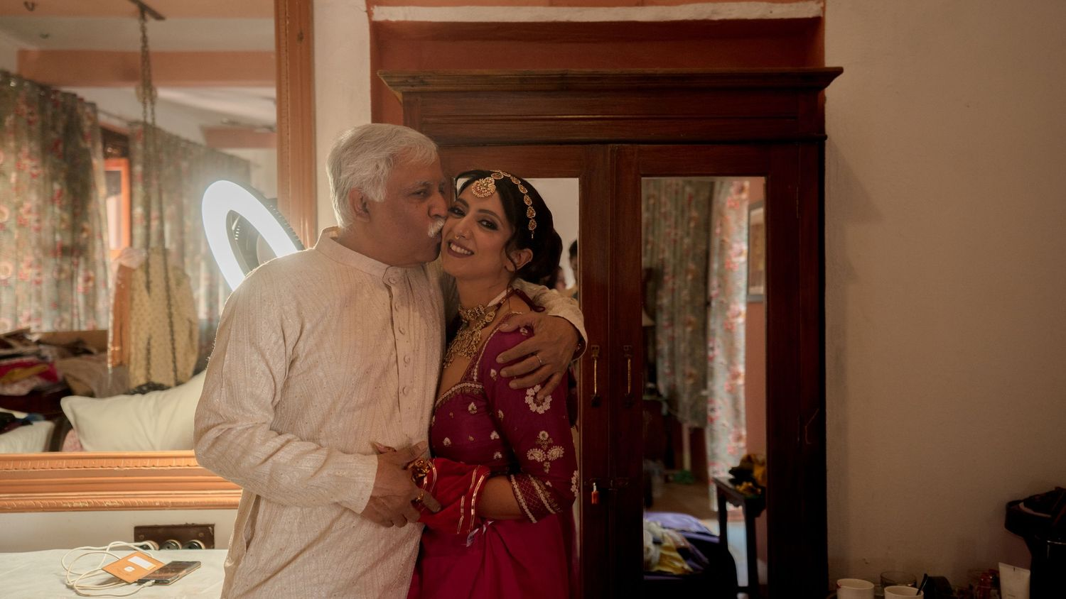 father kissing bride candid emotional wedding moment indoor bridal preparation