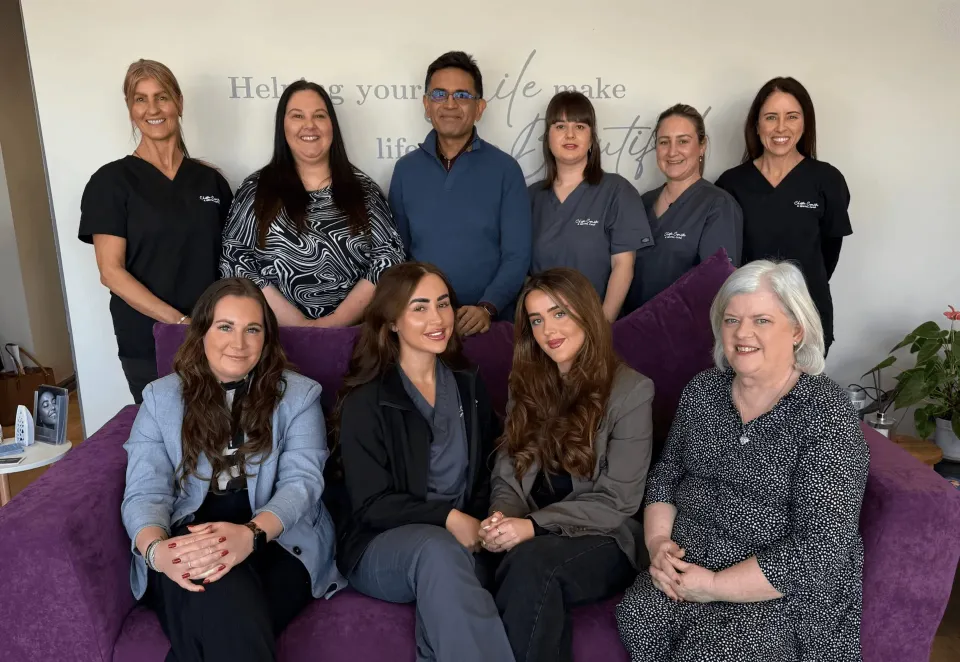 The Team of Dentist and Nurses at Chester Cosmetics & Dental Care sat on a couch and some standing behind
