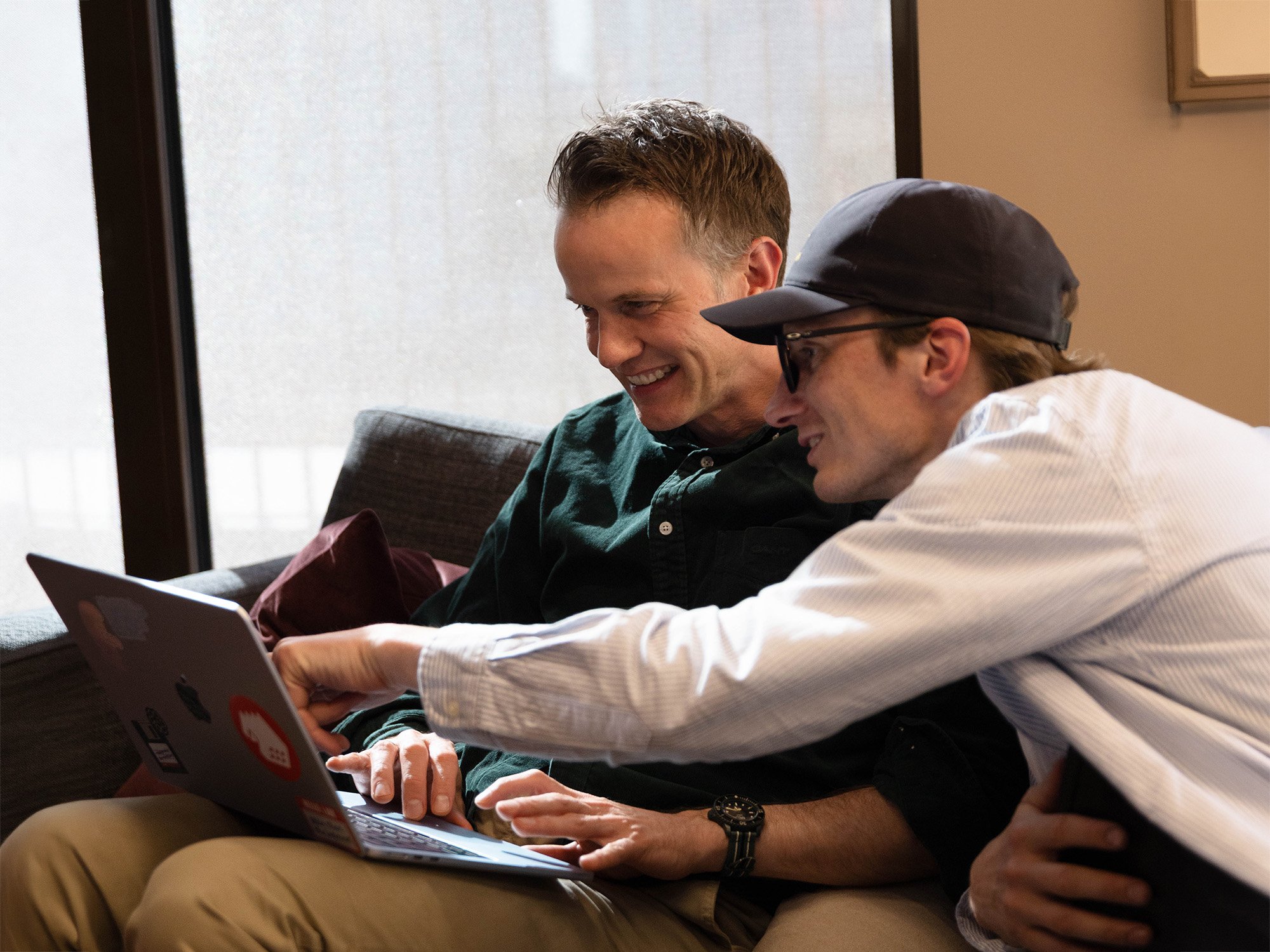 To teknologer samarbeider smilende foran en Mac