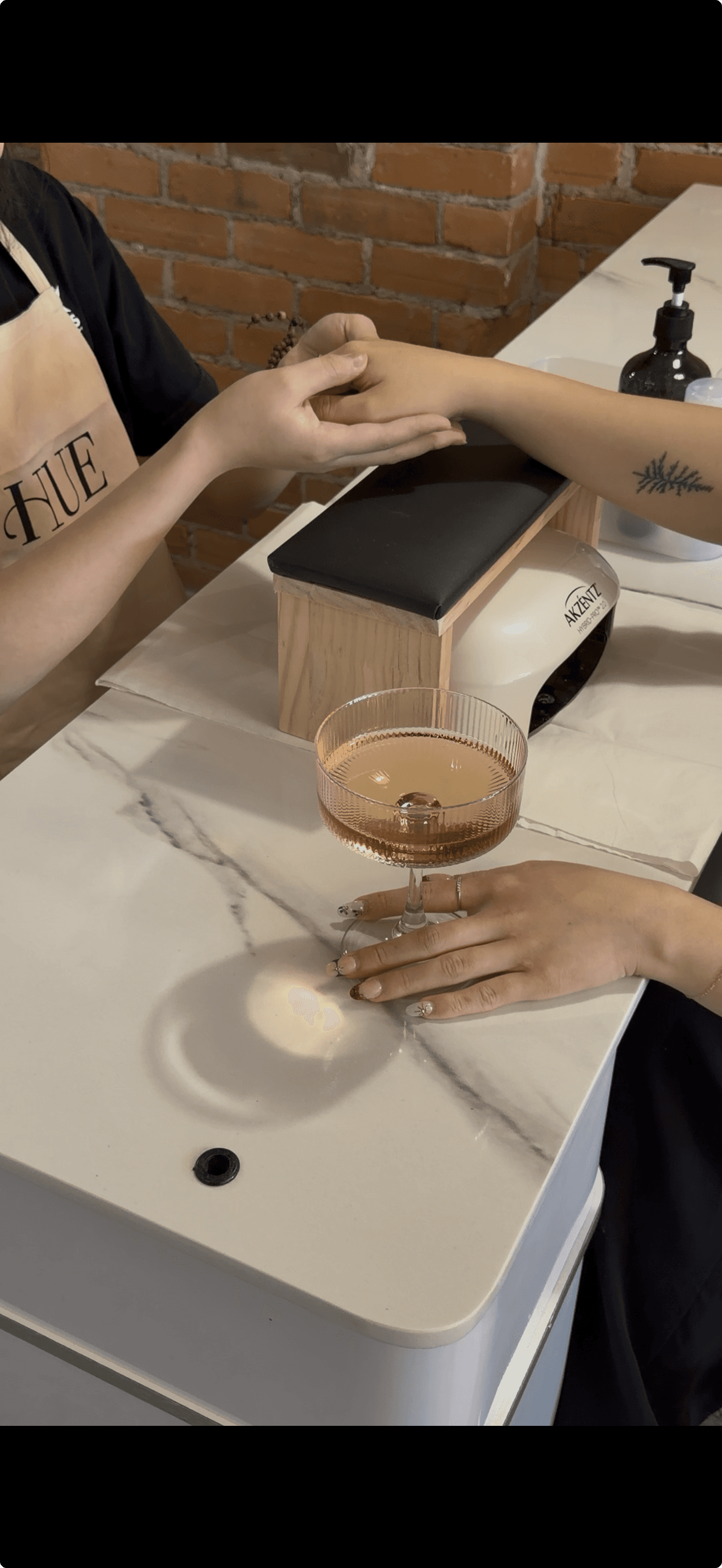 A luxurious bathtub filled with water and floating rose petals, surrounded by candles and greenery. The soft lighting creates a tranquil and romantic spa-like atmosphere.