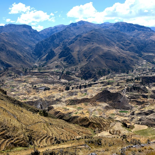一個有梯田和山脈的山谷，在部分多雲的藍天之下。