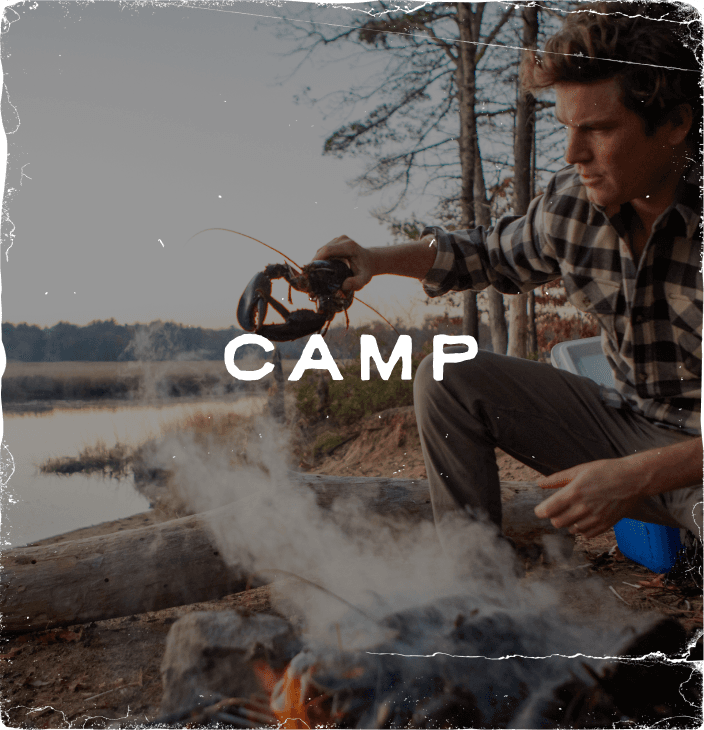 Rustic photograph of a man holding a lobster above a camp fire labeled 'Camp'