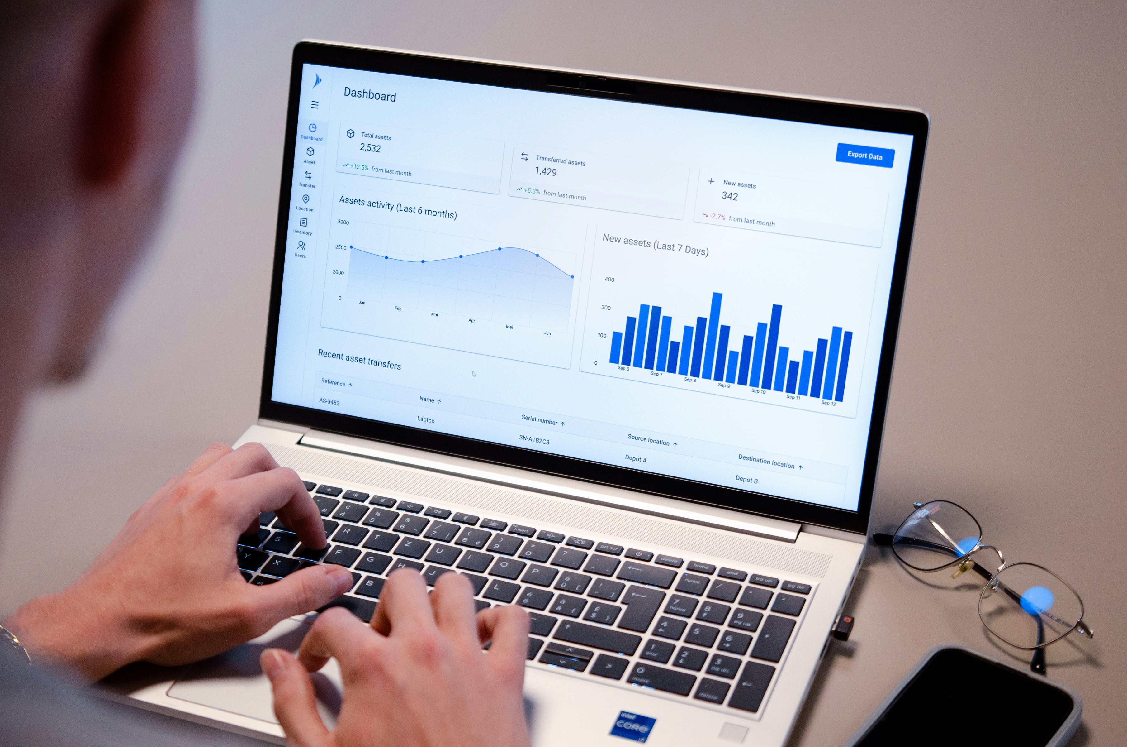 Person typing on laptop with data charts on screen