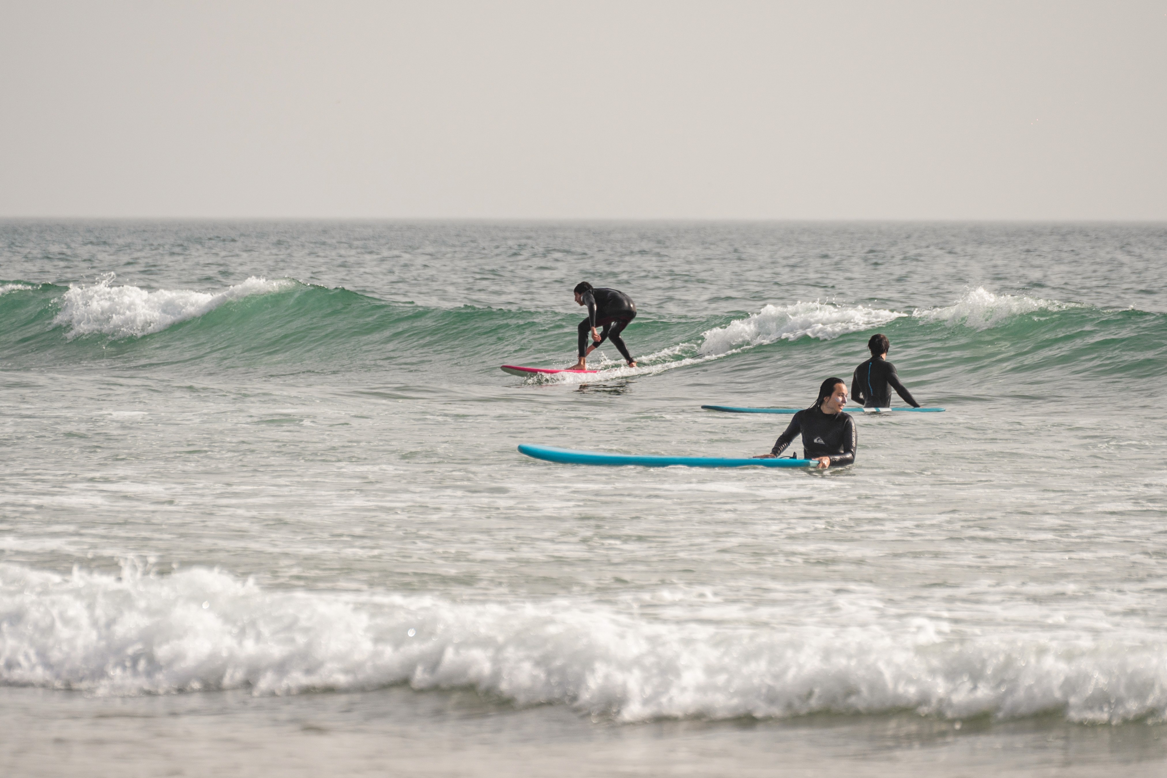 a group of people carrying surfboards on top of a beach
