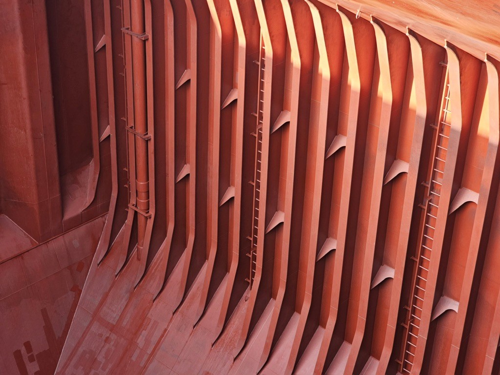 Clean, dry bulk carrier cargo hold with coated frames and ladders, prepared to grain-clean cargo readiness standards with inspection-ready condition.