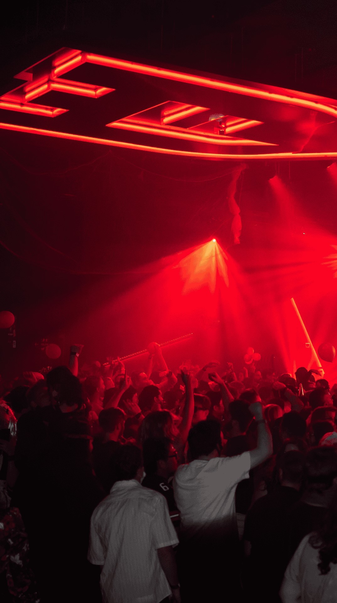 a hazy nightclub lit by red lighting with a crowd dancing