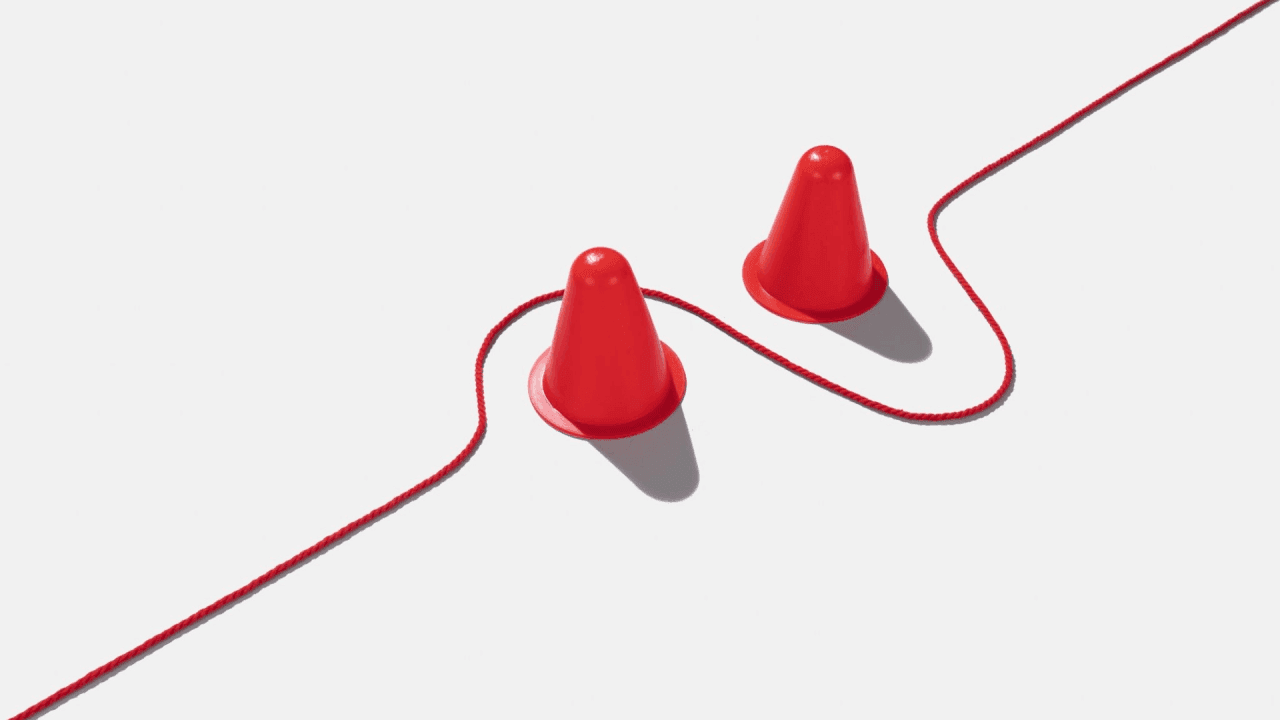 Red rope navigating around two orange traffic cones, illustrating adaptability and the need to change course when encountering obstacles.