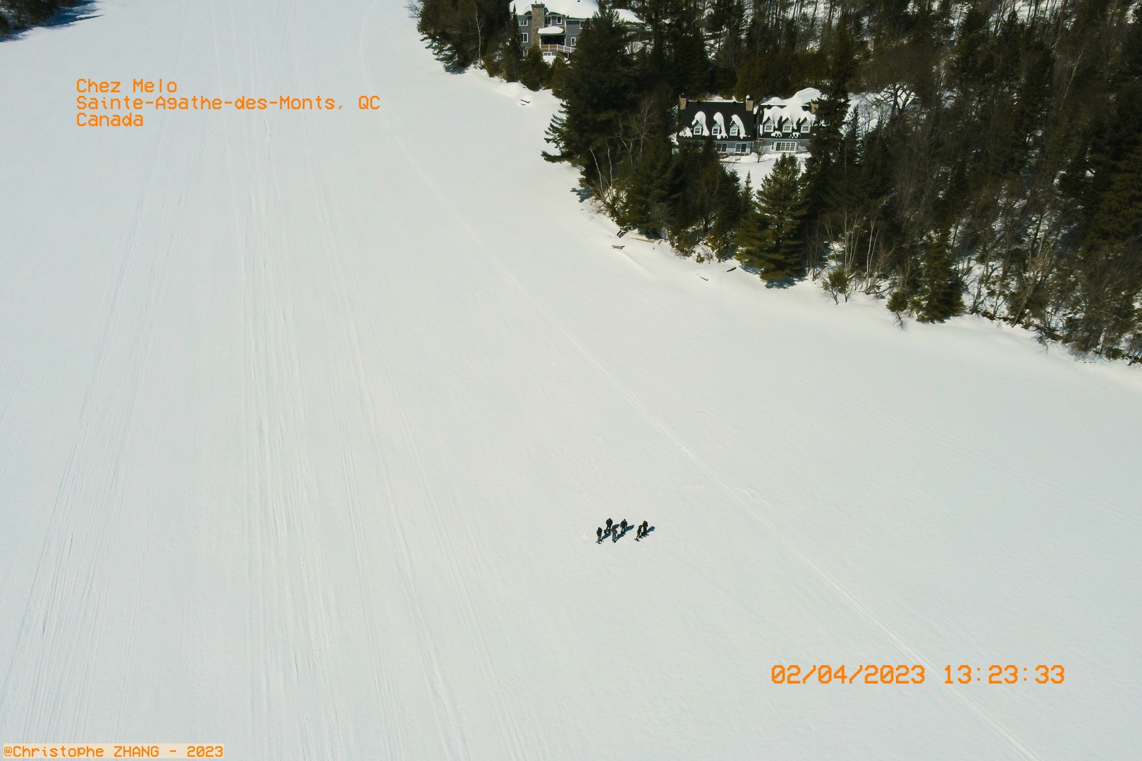 Groupe marchant sur un lac gelé entouré de forêts enneigées.