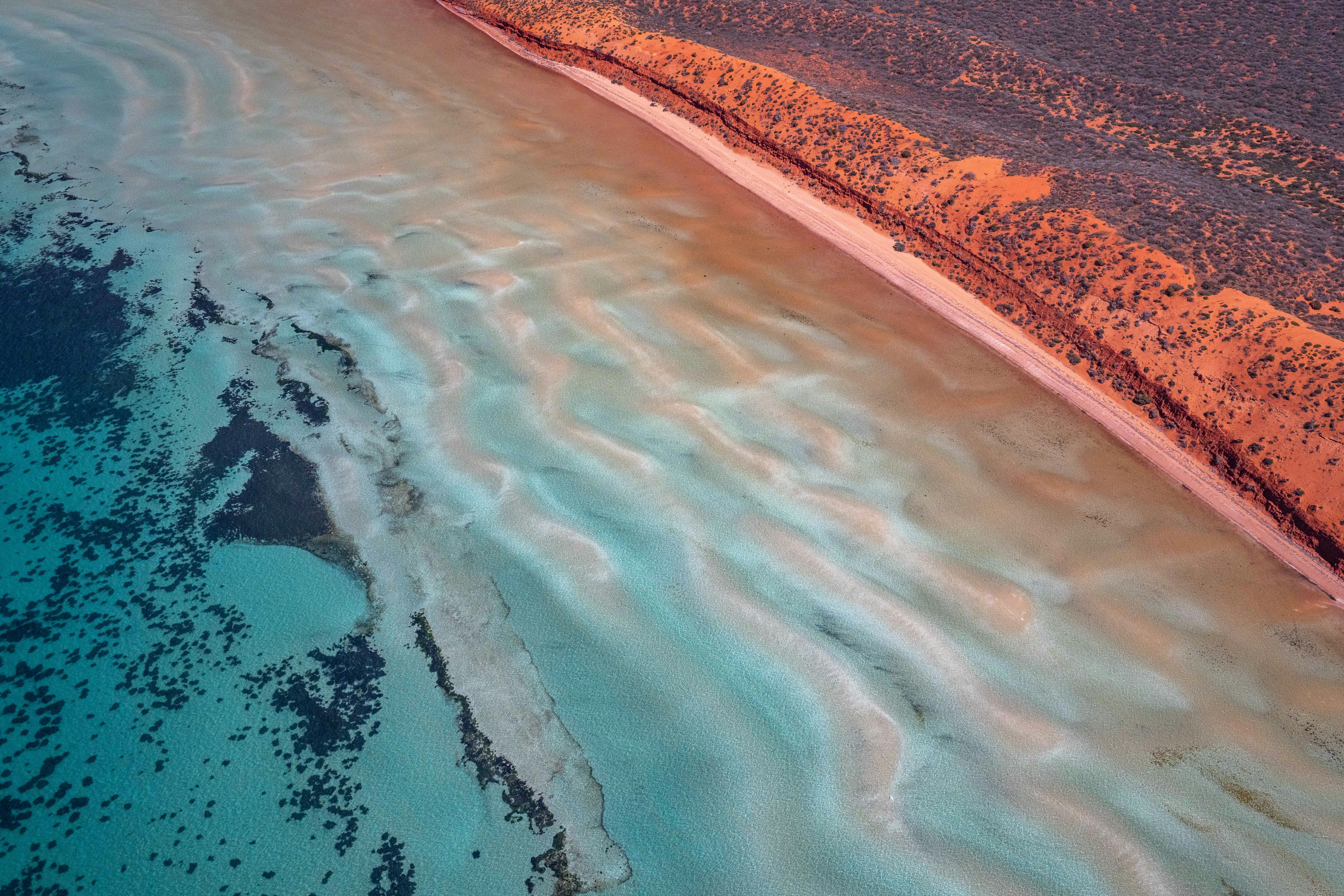 Aerial view of a sandy coastline with shallow turquoise water