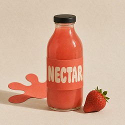 A bottle of red strawberry juice labeled "NECTAR" sits on a beige surface beside a fresh strawberry, evoking a fresh and natural vibe.