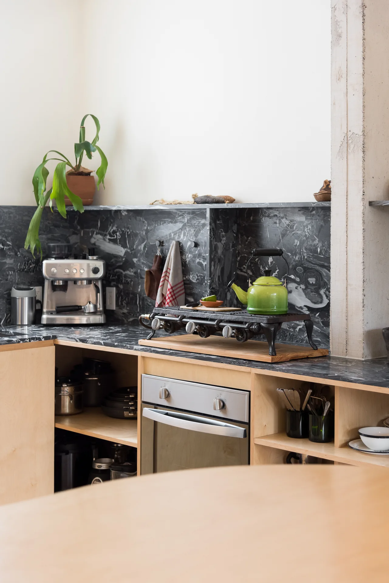 Casa Oficina, cocina con frente de mármol negro y carpintería de madera clara