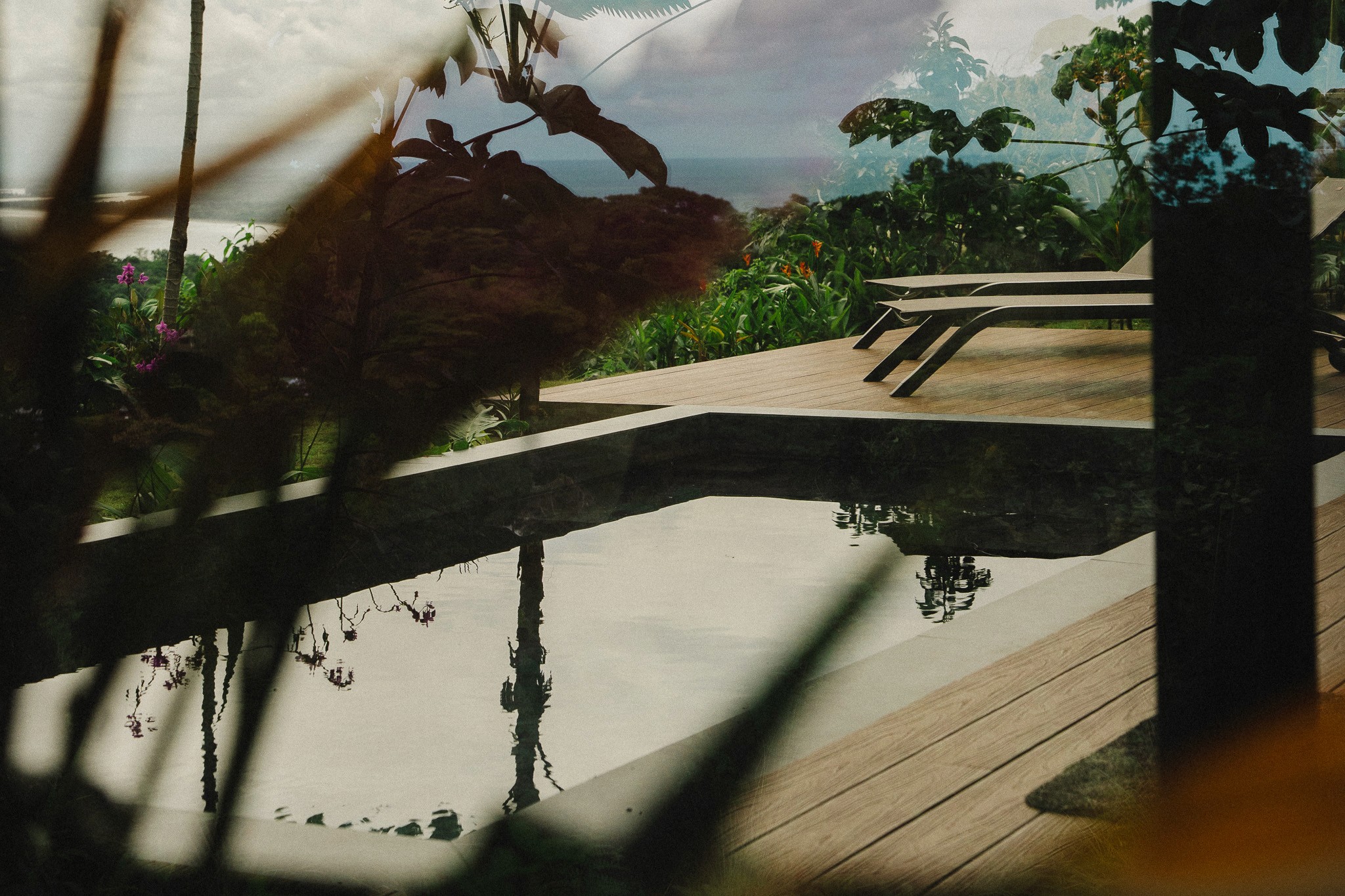 nfinity pool blending into the ocean view, minimalist sun loungers in soft neutral fabric, curved architecture