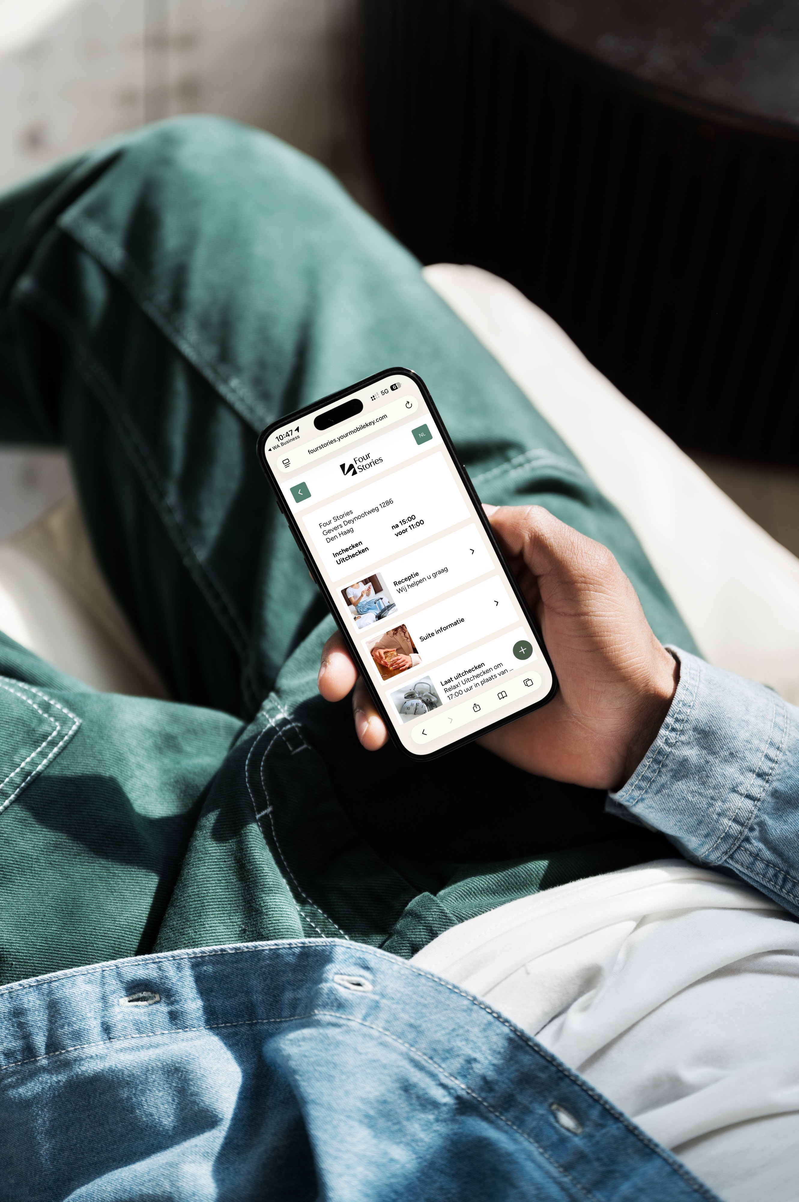 Persoon die ontspannen op bed zit en de Four Stories webapp op een smartphone gebruikt voor digitaal inchecken