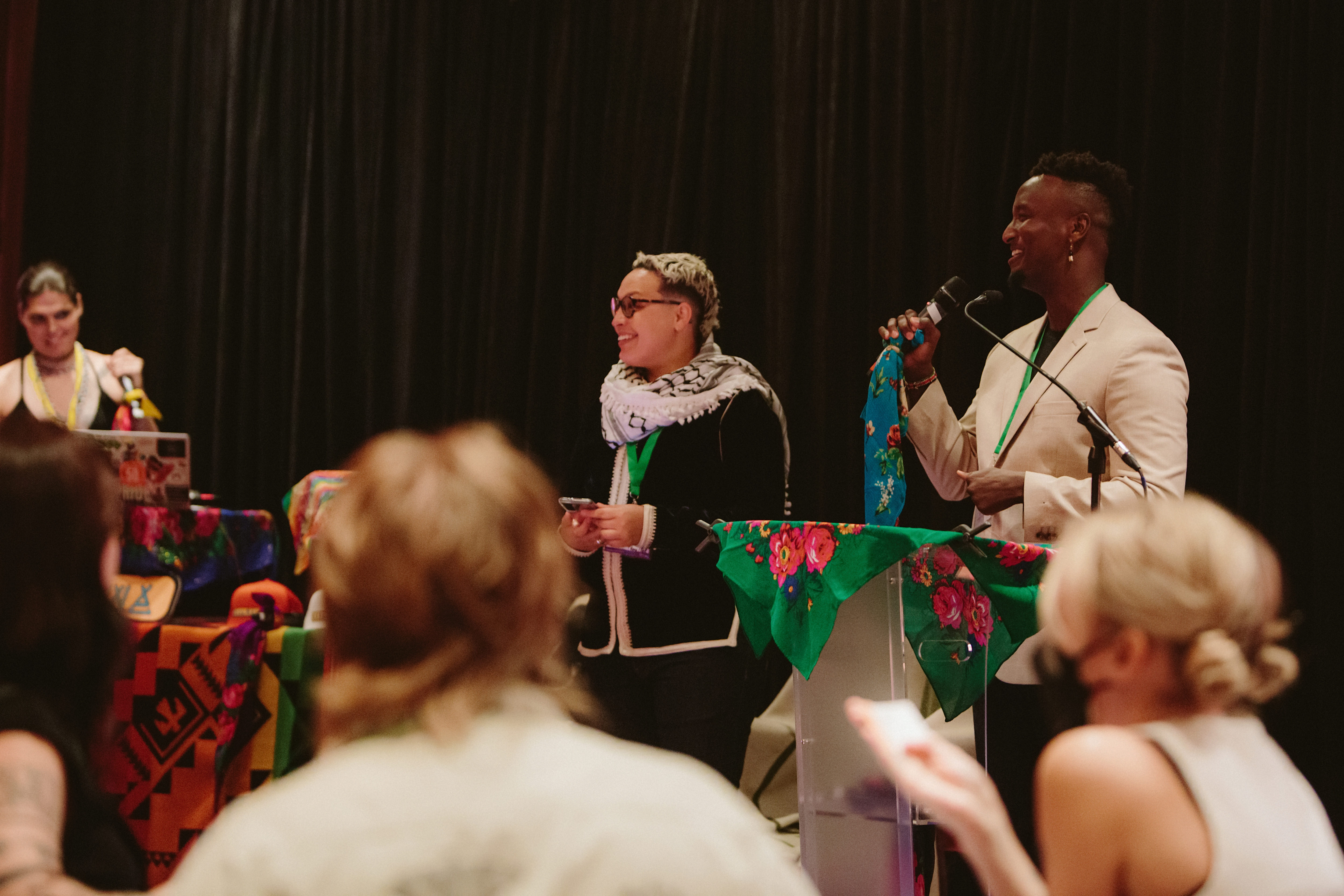 A group of people engage in discussion, with two individuals speaking to an audience in a conference setting.