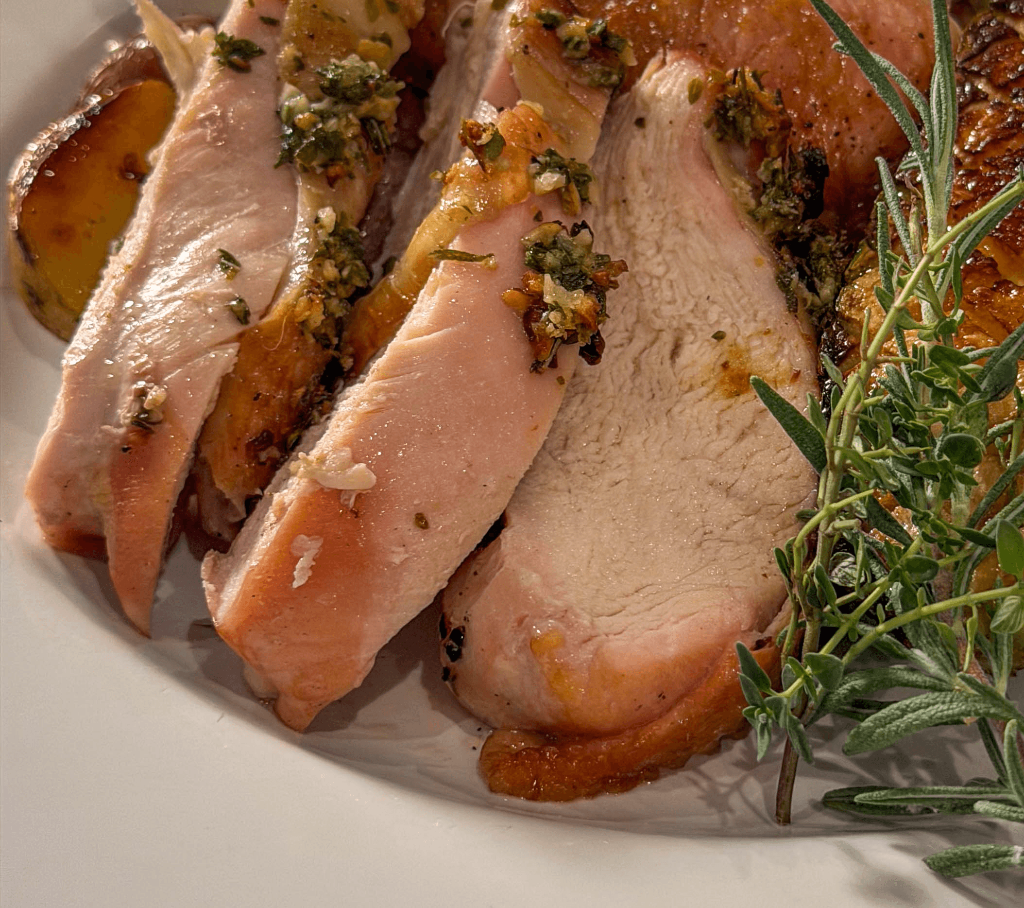 sliced chicken with skin and sprigs of herbs