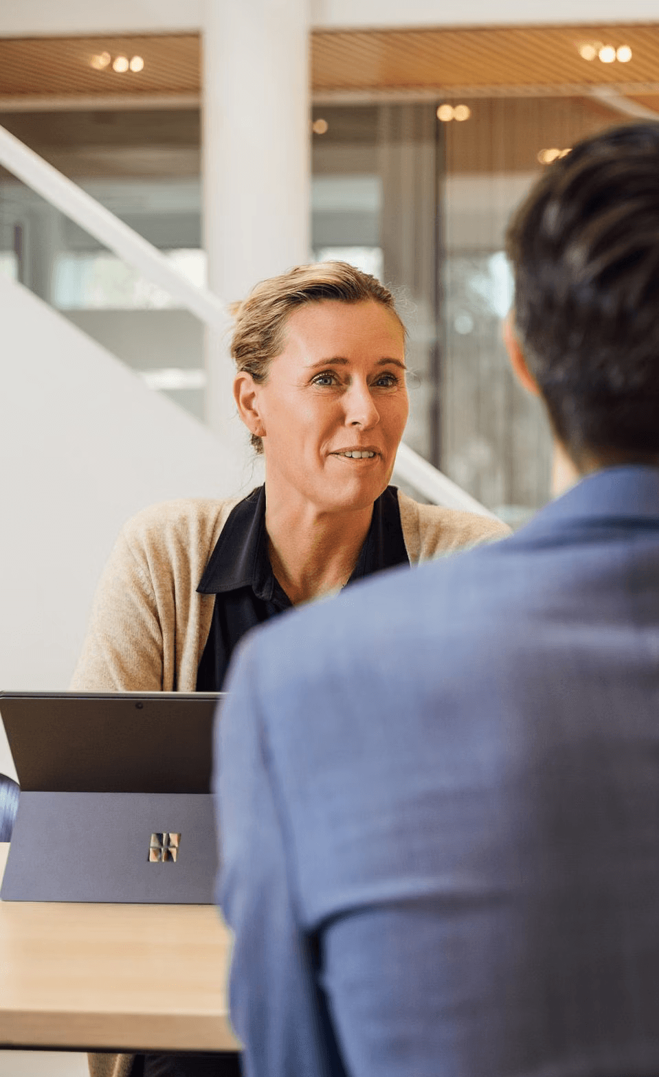 A woman in a suit sitting at a table talking to a man in a suit