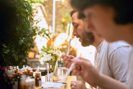 A group of people engaged in a perfume-making workshop, carefully blending scents and enjoying the creative process in a well-lit, relaxed environment.