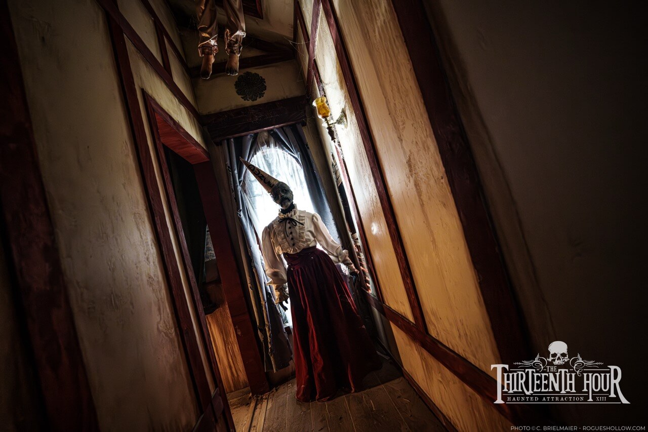 Costumed figure in a narrow haunted house hallway