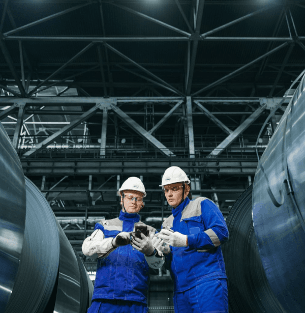 Dos técnicos con casco revisando una instalación industrial