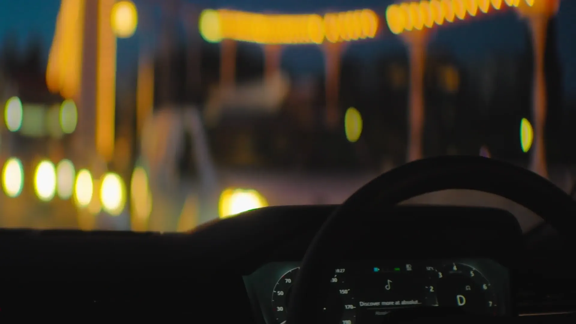 Traces para Range Rover: primer fotograma de contenido multimedia que muestra interior de un coche de noche con el salpicadero y luces de ciudad desenfocadas.