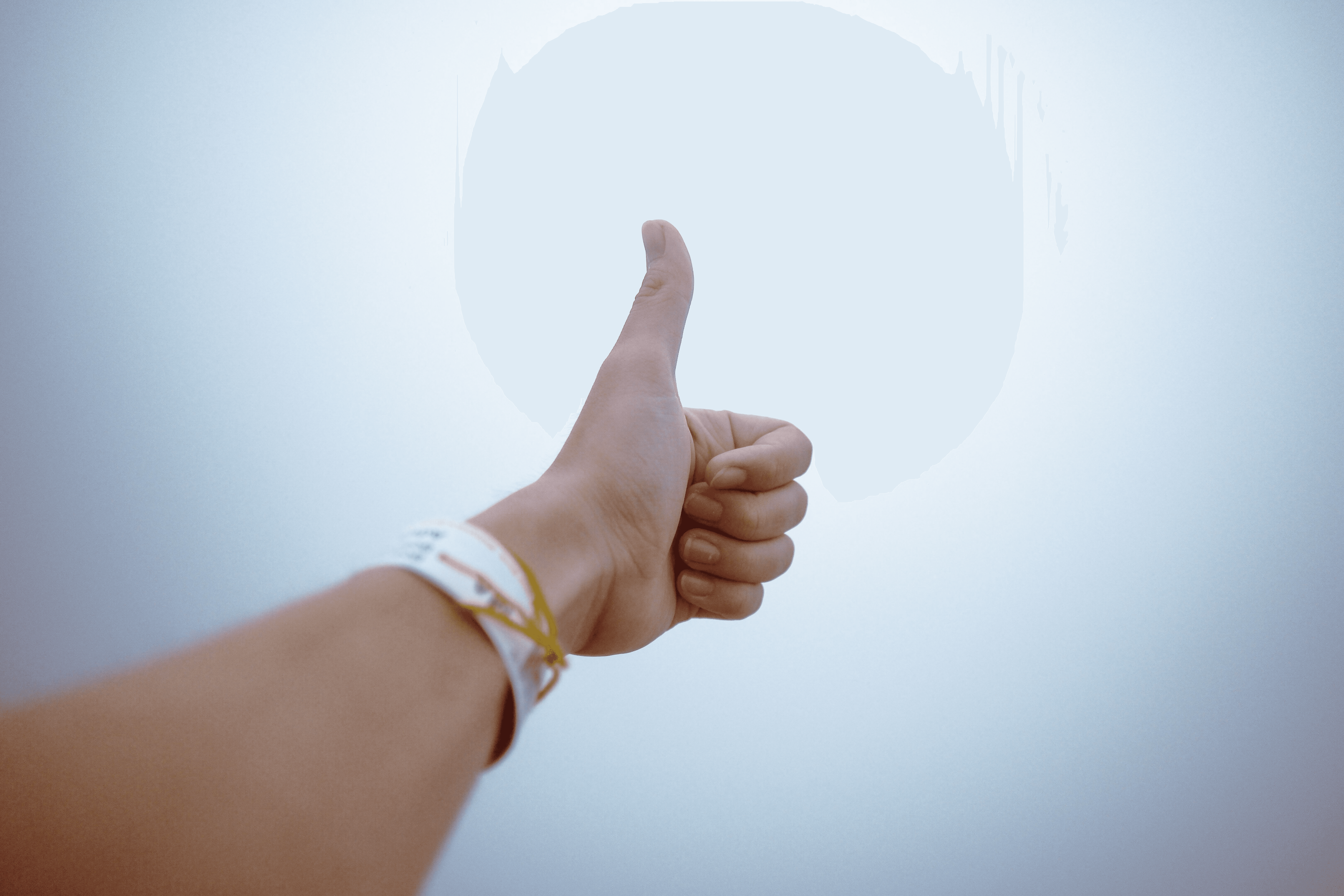 A hand giving a thumbs up gesture symbolizes approval and positivity.
