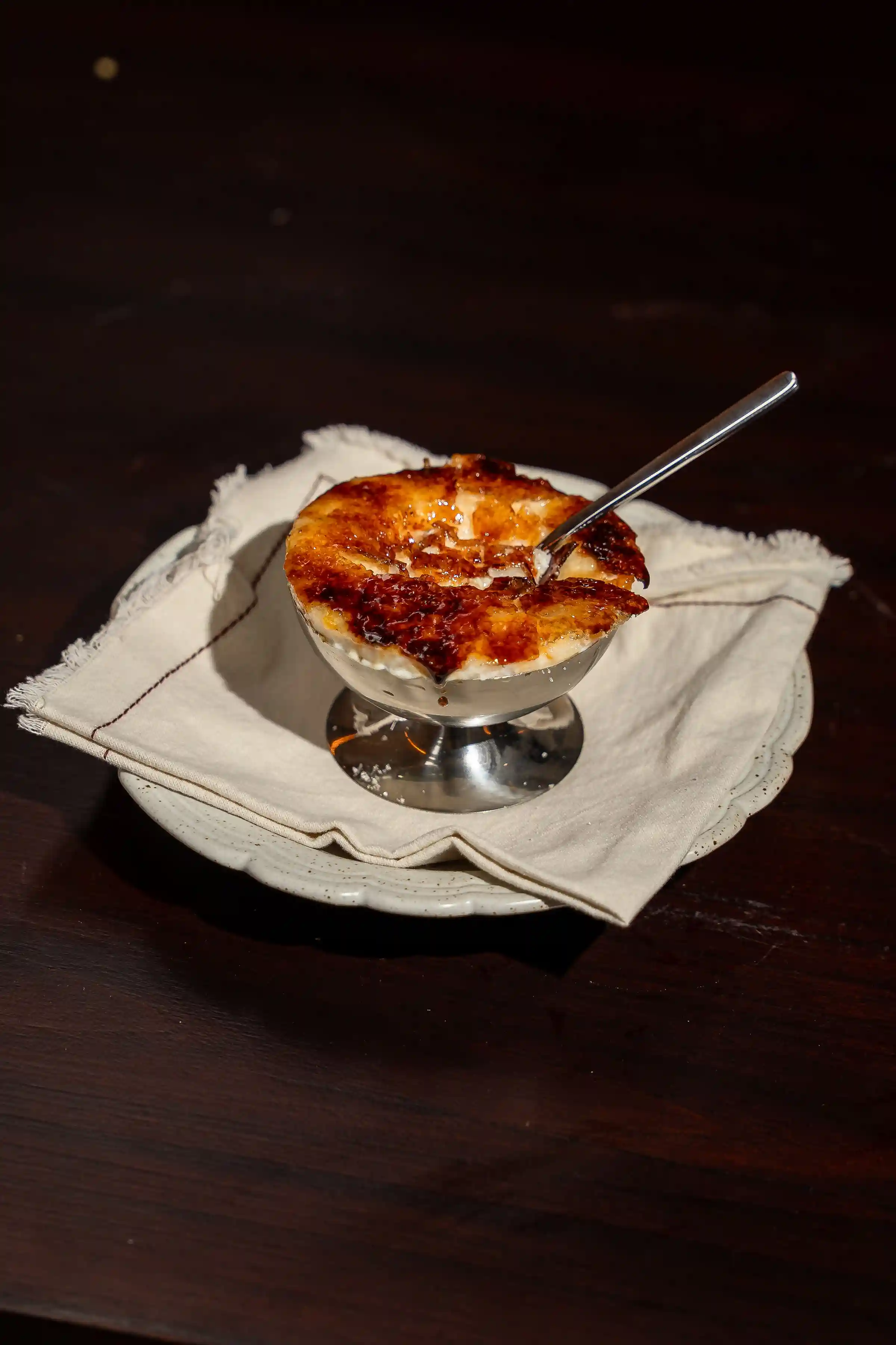 Caramelized dessert served in a silver bowl on linen napkin at Nari Restaurant Ubud
