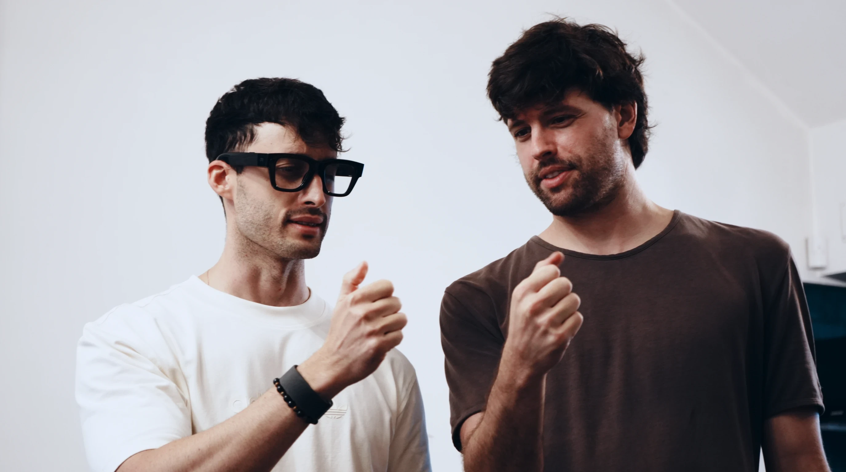 Two people demonstrating smart glasses and wrist-worn controls.