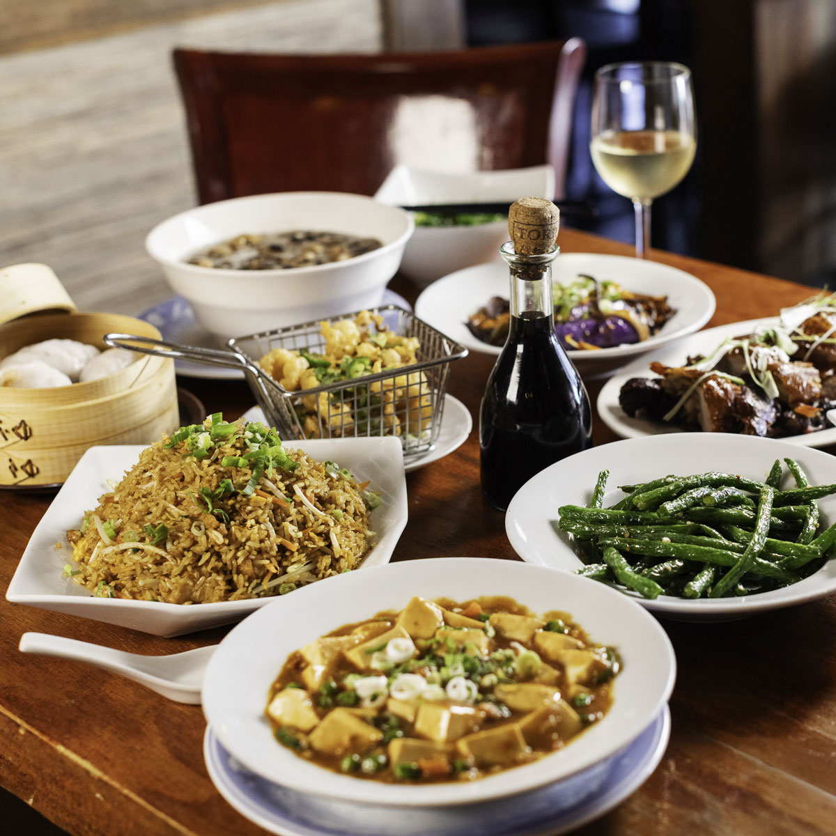 Close-up of steamed shrimp dumplings (har gow) in a bamboo steamer basket on a wooden table.