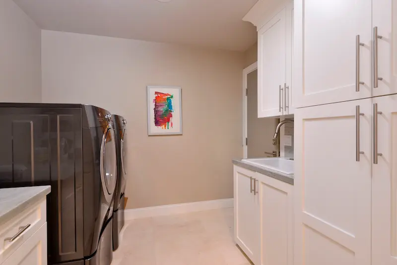 Functional laundry room with modern appliances and ample cabinetry in Harbor Ridge Transitional Remodel.