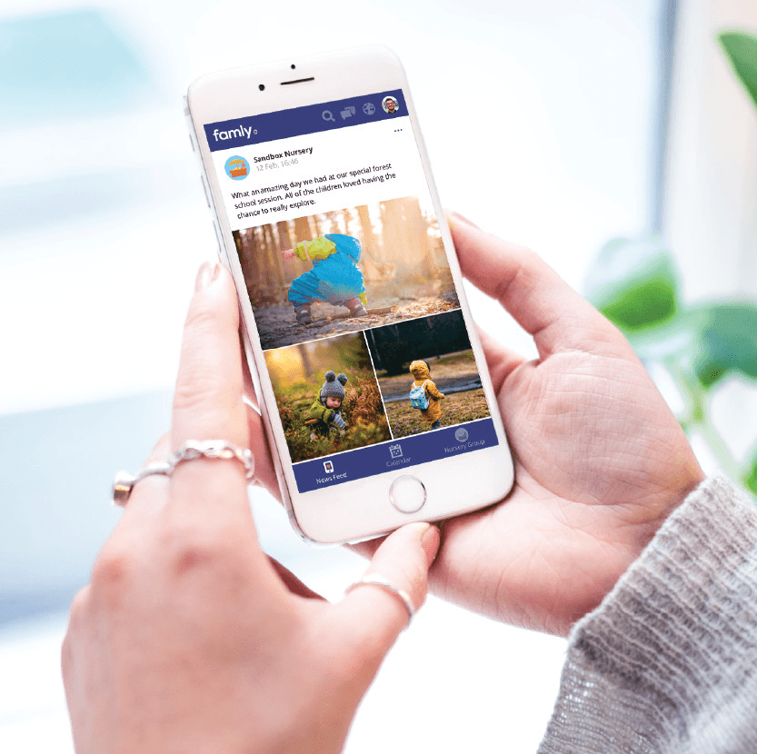 Person holding a smartphone displaying a family photo album app with pictures of children and nature.