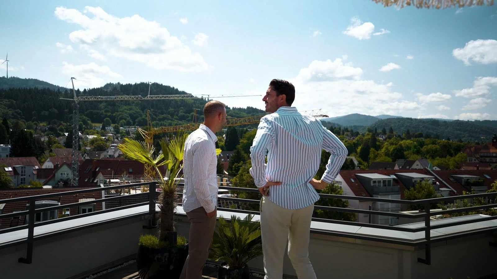 Dennis Cofani und Christian Rees auf einer Dachterrasse mit Blick über Freiburg und den Schwarzwald