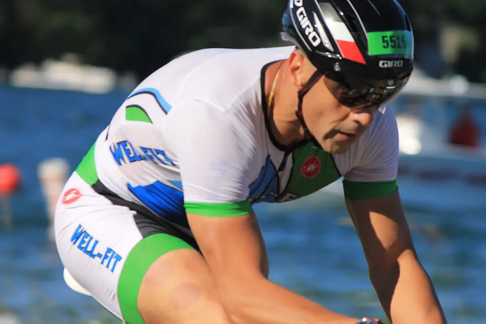 Male triathlete in Well-Fit race kit riding in aero position during a triathlon bike leg