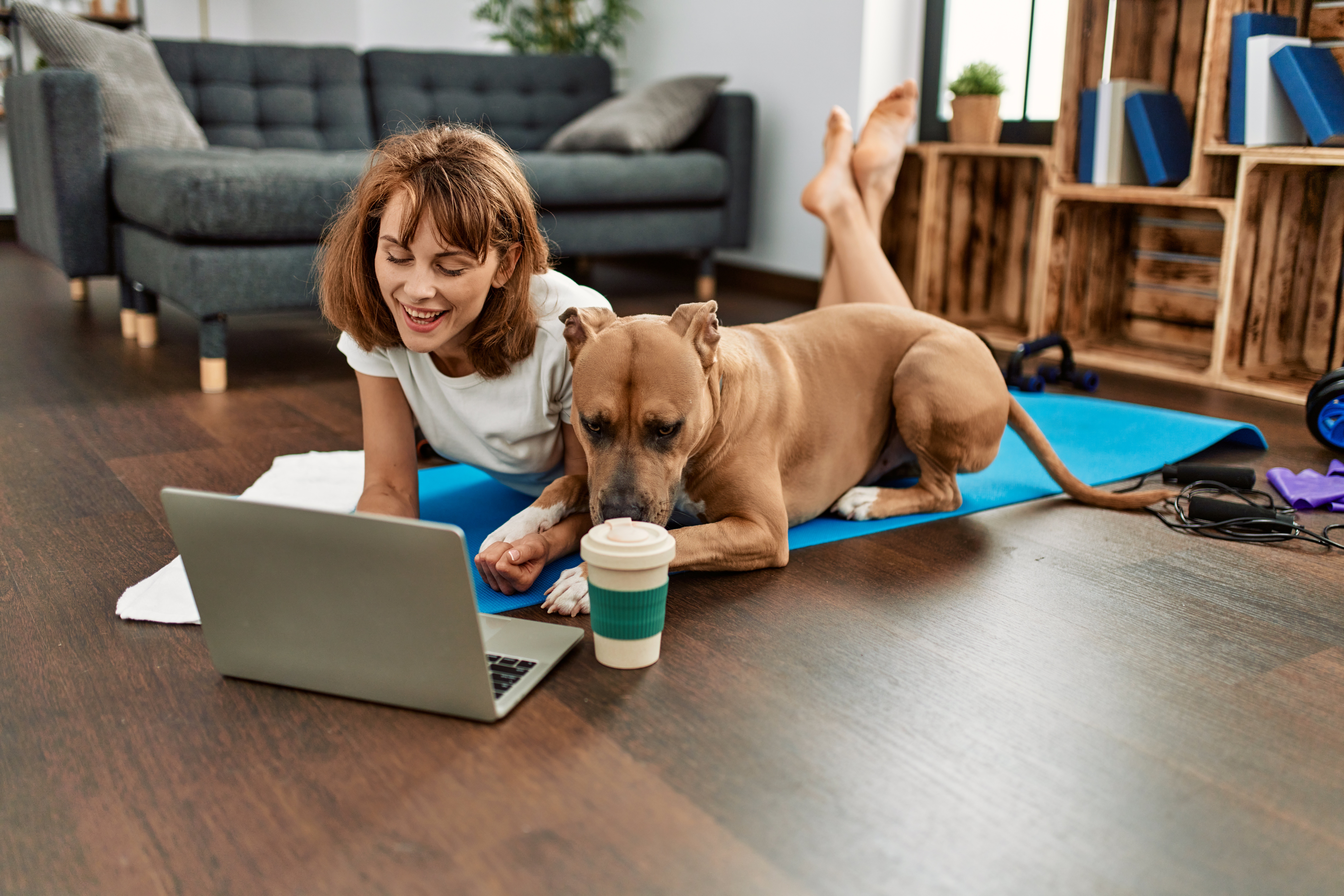 Woman stretching on a yoga mat with her dog beside her on hybrid flooring that handles pet mess, resists stains, and stays slip-safe in Brisbane homes.