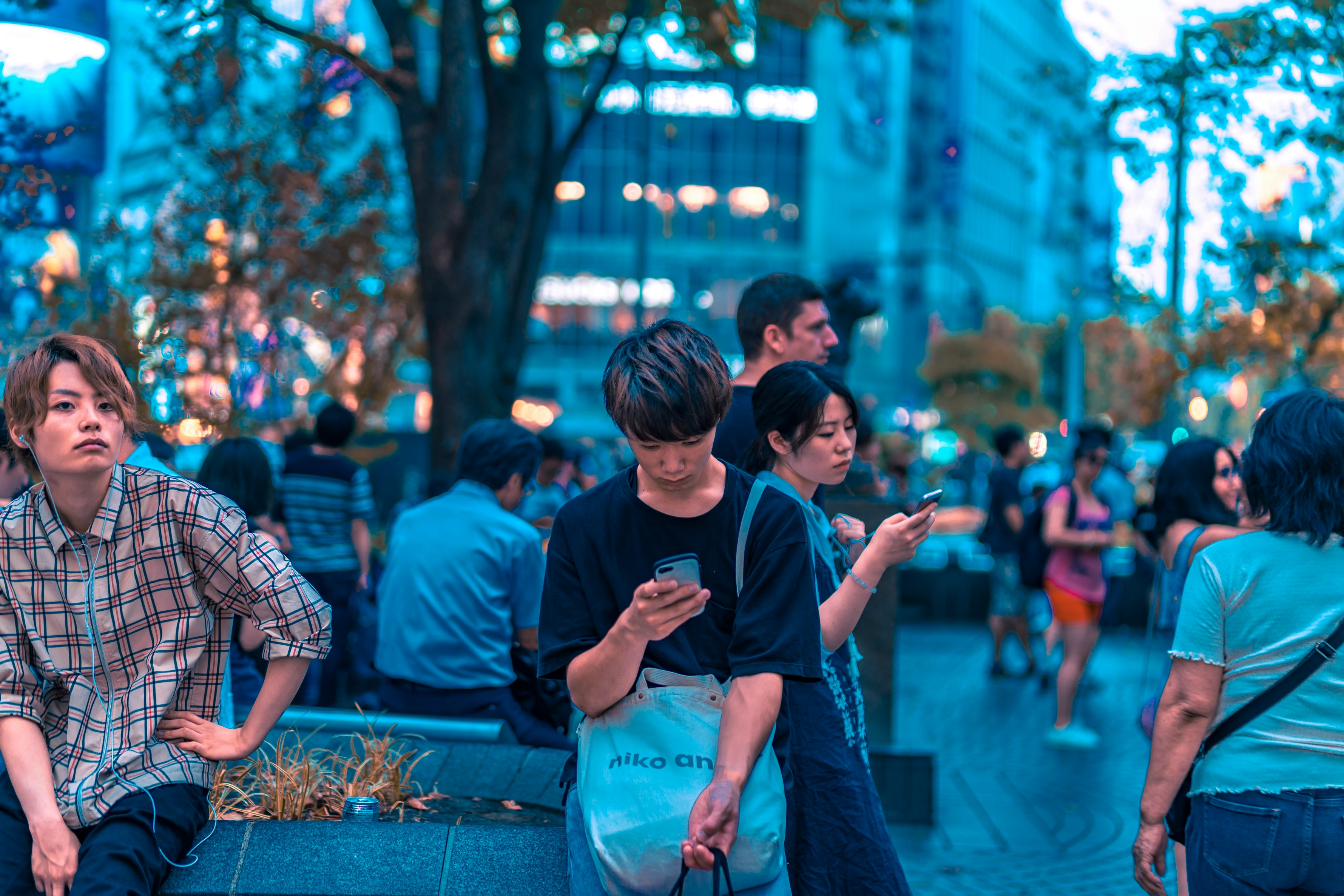 selective focus photography of man sitting on concrete chair while holding smartphone