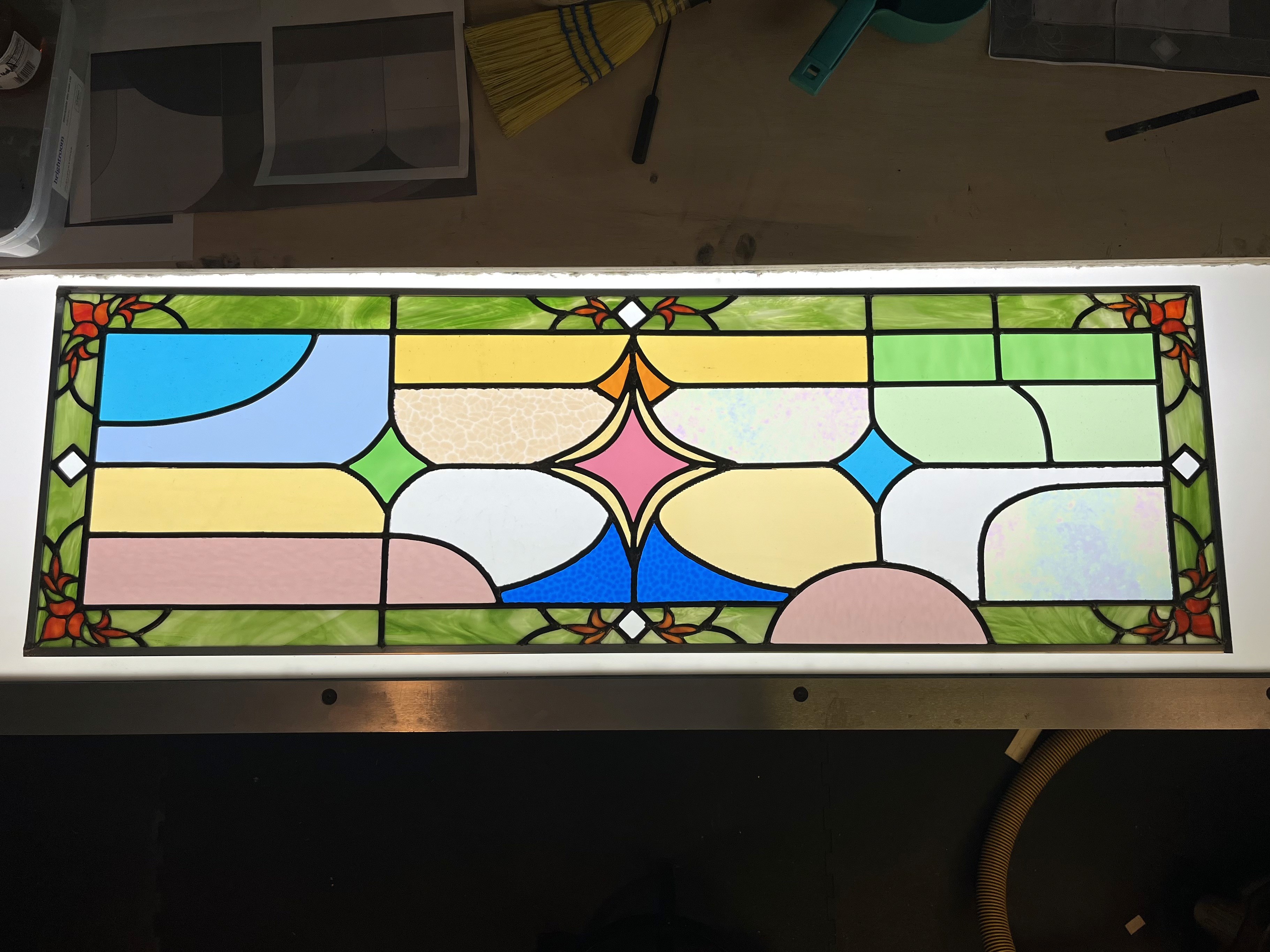 Handmade stained-glass window panel with a red rose and green leaves set above a city skyline