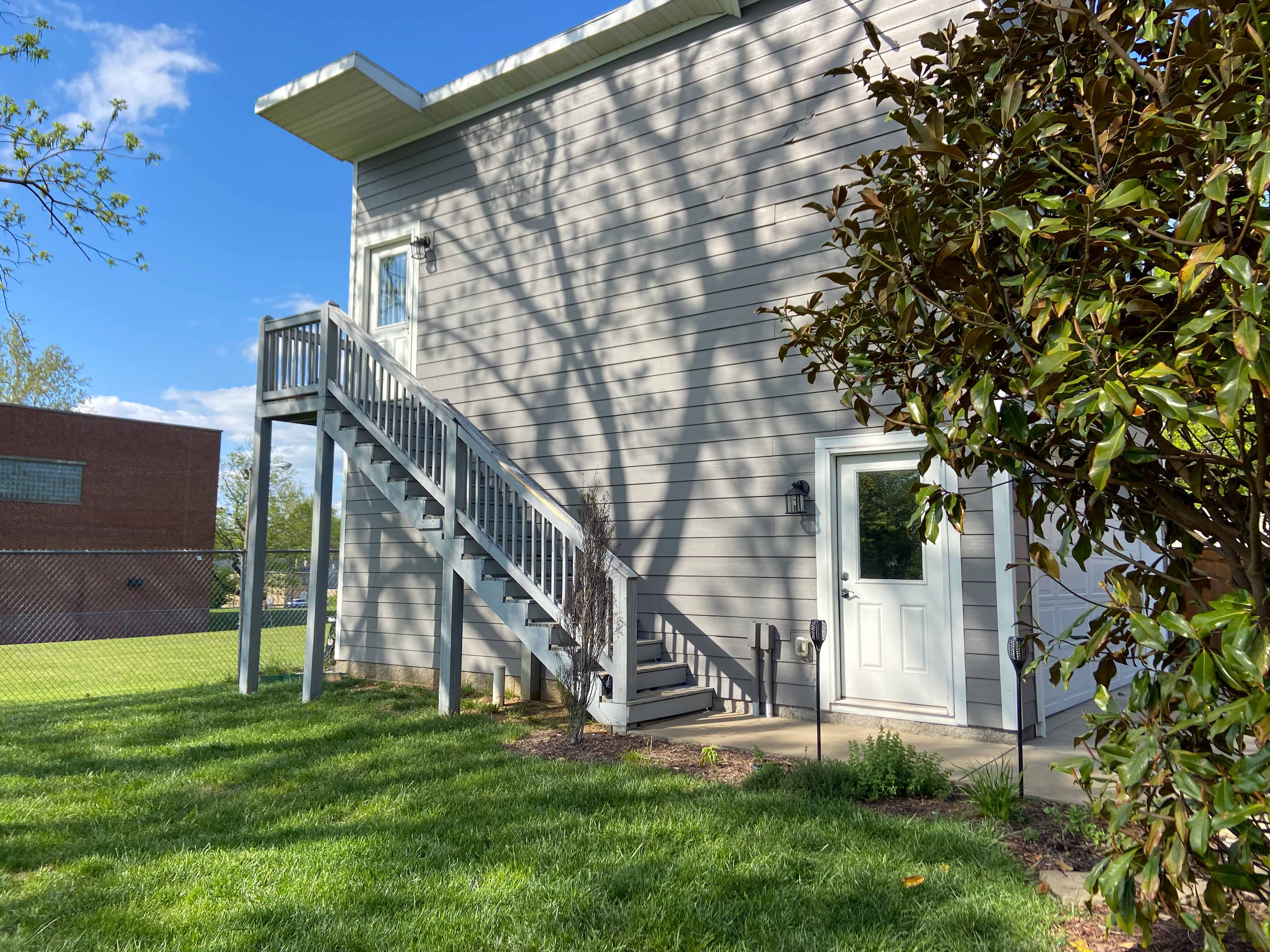Gray house with stairs and new planting bed below.