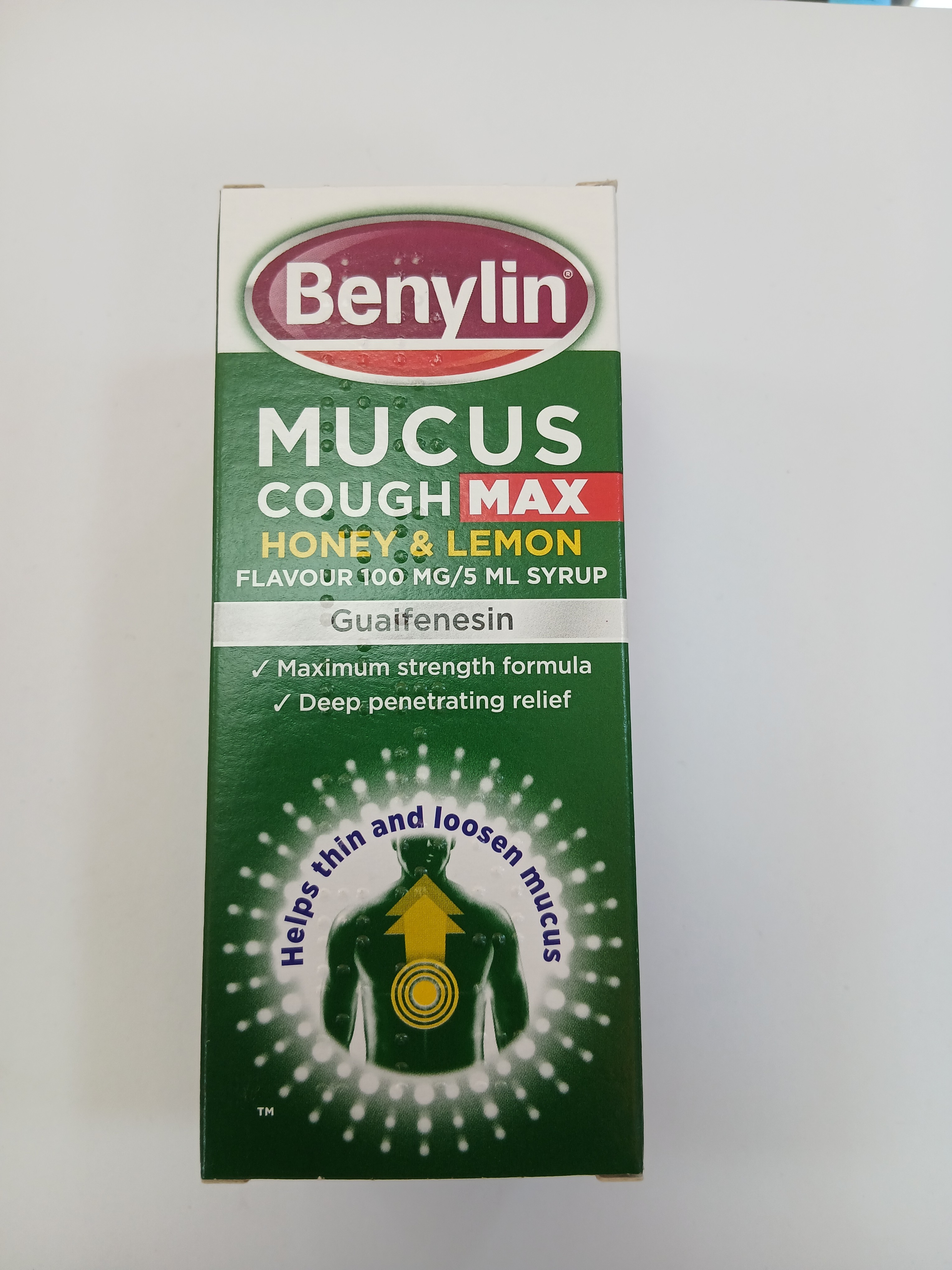 Green and white cardboard box packaging for a honey and lemon-flavored syrup featuring a yellow and red label with text and an illustration of a person with a chest relief graphic.