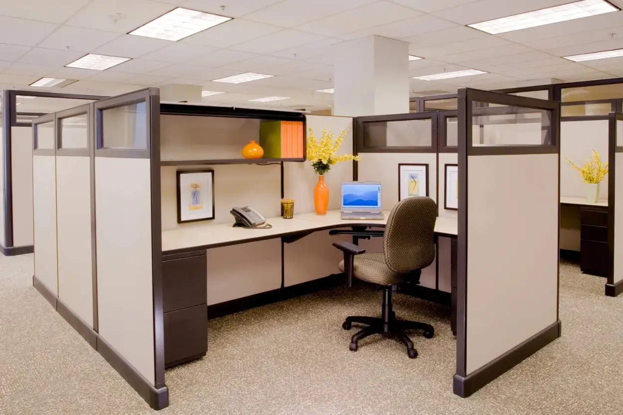 Modern office cubicle with L-shaped desk, ergonomic chair, and modular partitions.