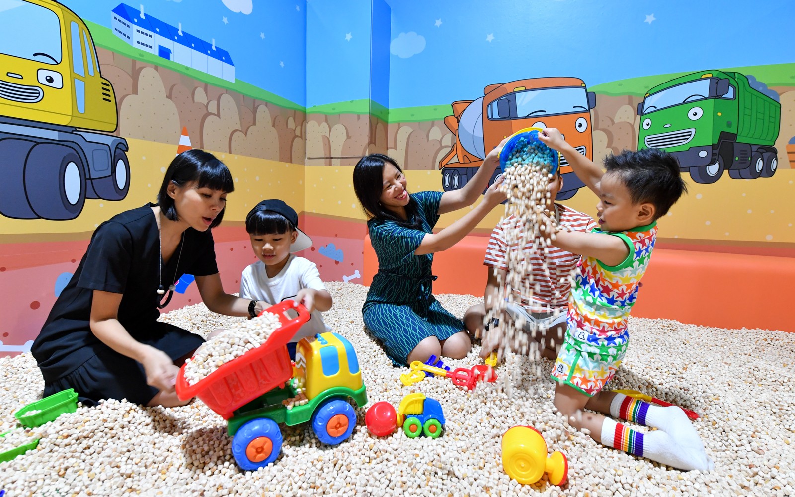 Children playing with toy trucks and beans at Tayo Station indoor playground.