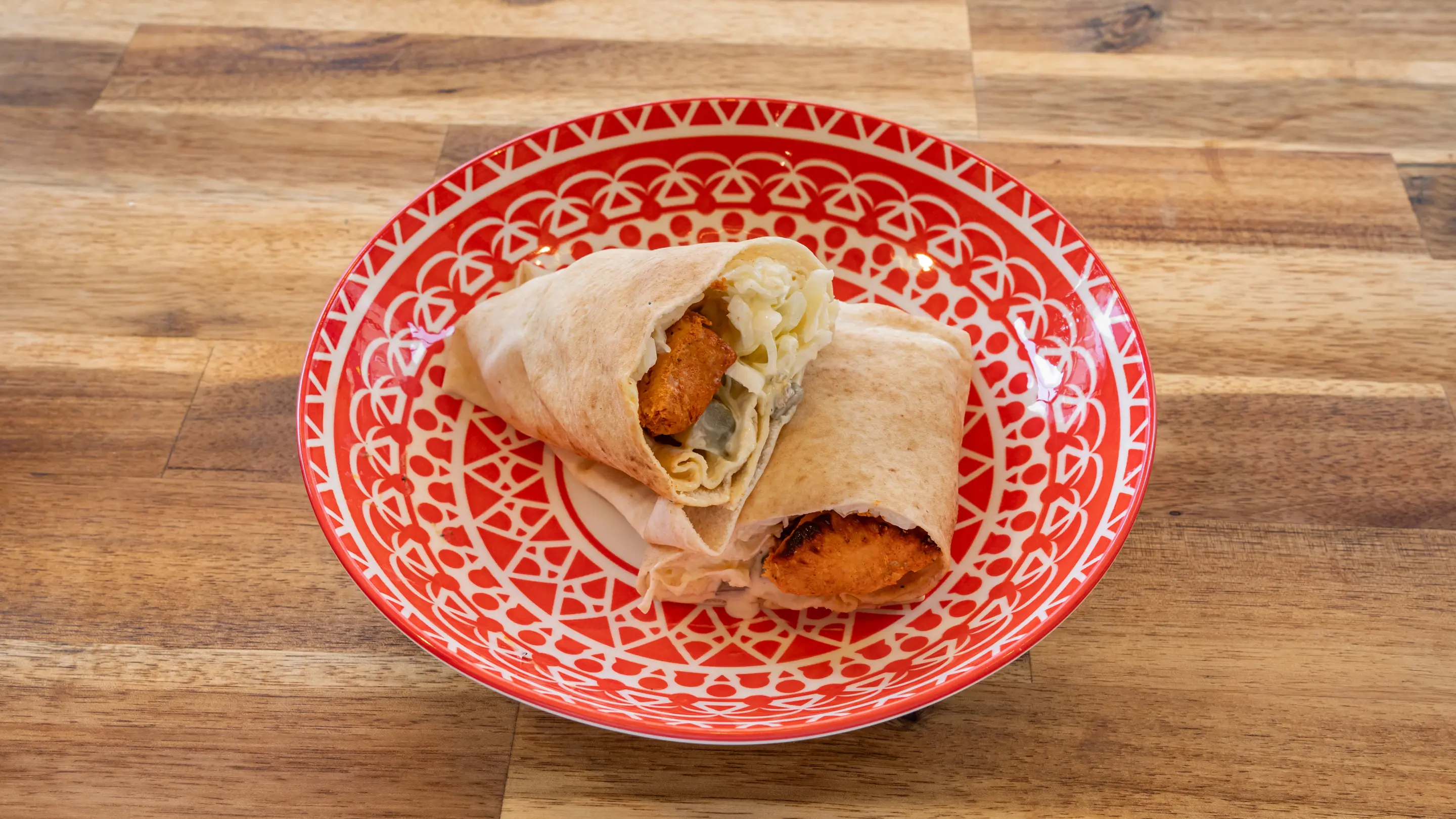 Sandwich libanais garni de bœuf, servi sur une assiette verte avec garniture visible
