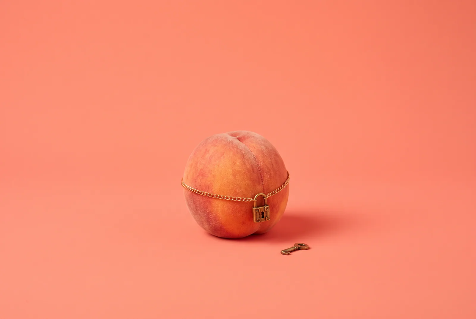 A peach wrapped in a thin gold chain with a small padlock, pairing a recovery app with a content blocker
