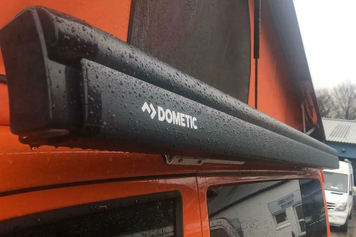 Dometic awning mounted on the side of an orange campervan