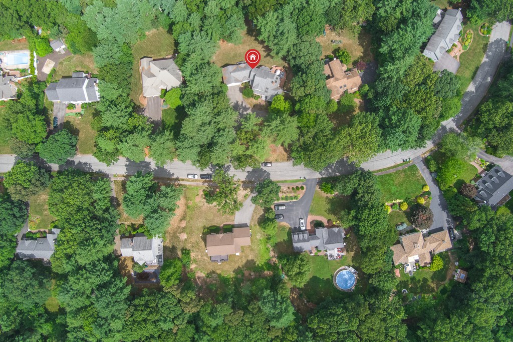 Modern kitchen with a wooden dining table, white chairs, and a hanging light fixture above.