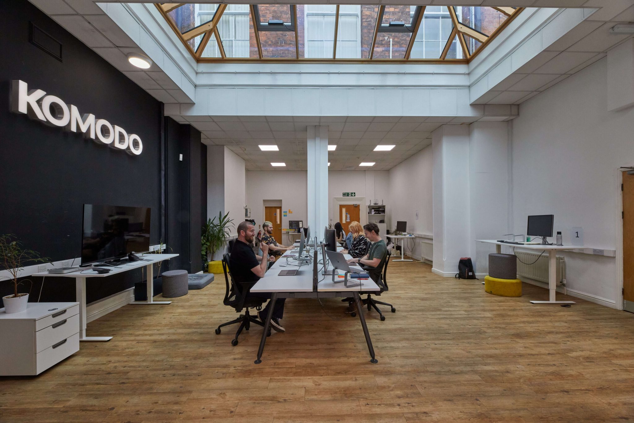 The Komodo studio. There's a long bank of desks in the middle of the room below a pitched glass ceiling.