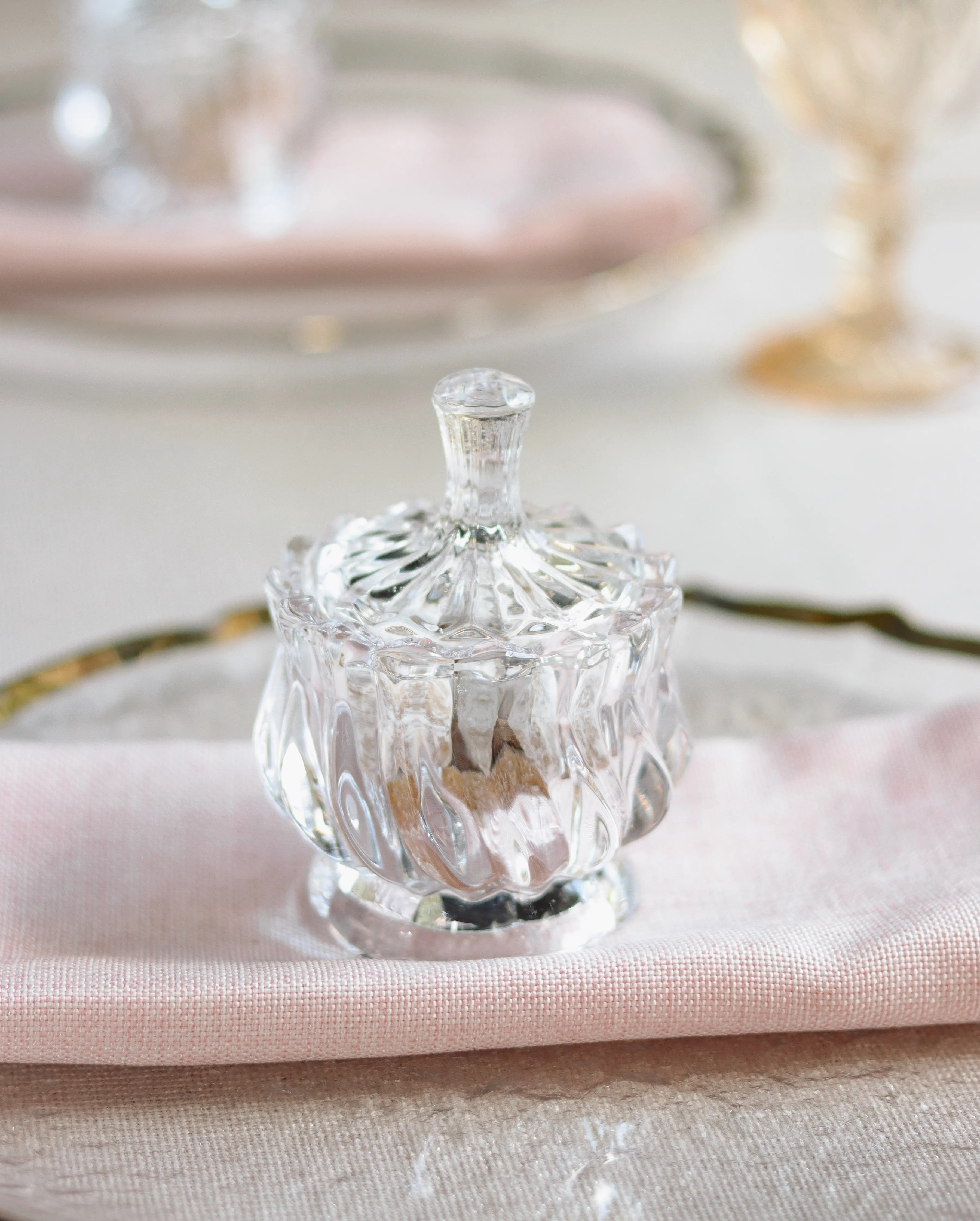 Frasco decorativo con tapa tallada sobre servilleta rosa