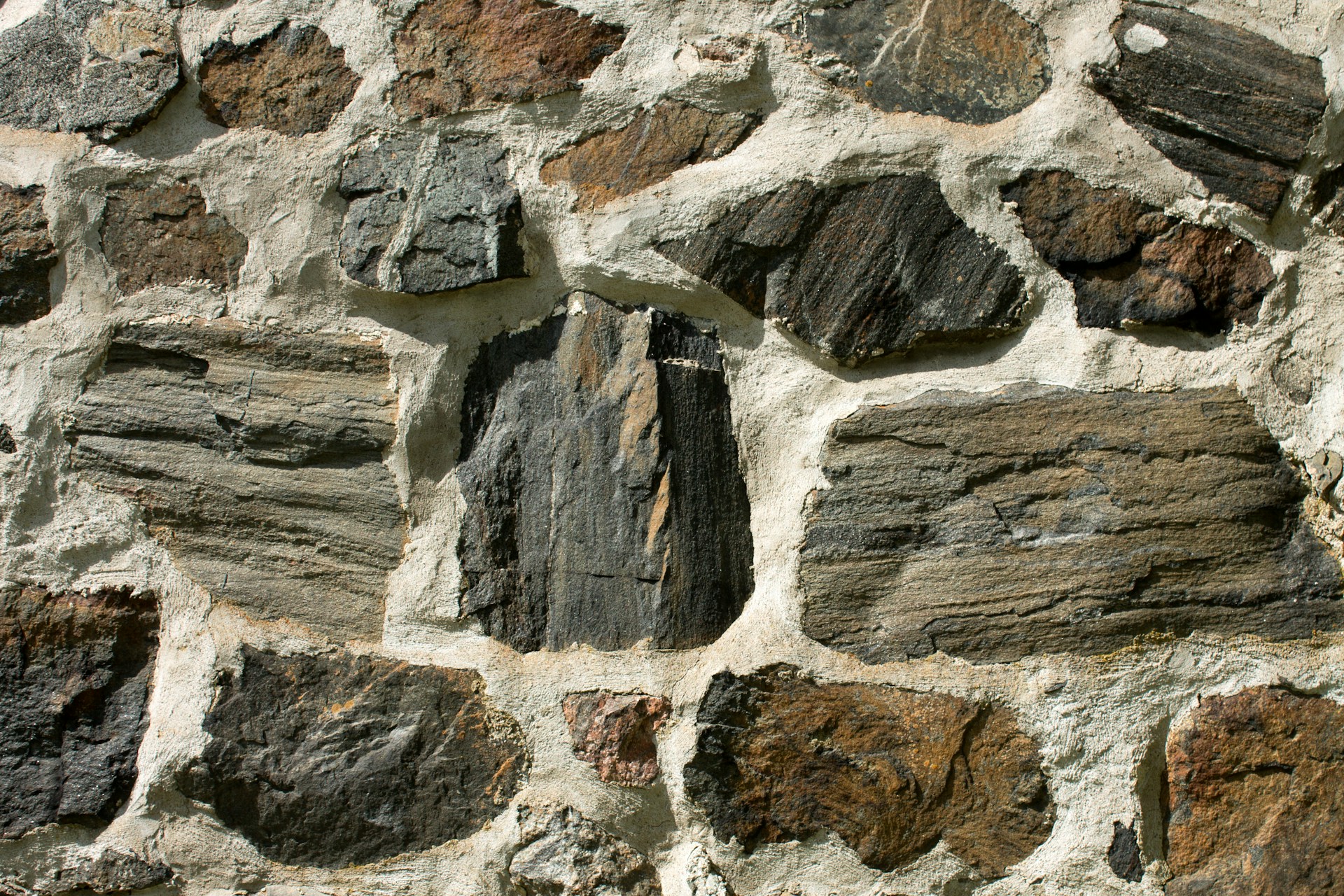 Mur de pierres naturelles irrégulières avec texture brute et joints apparents.