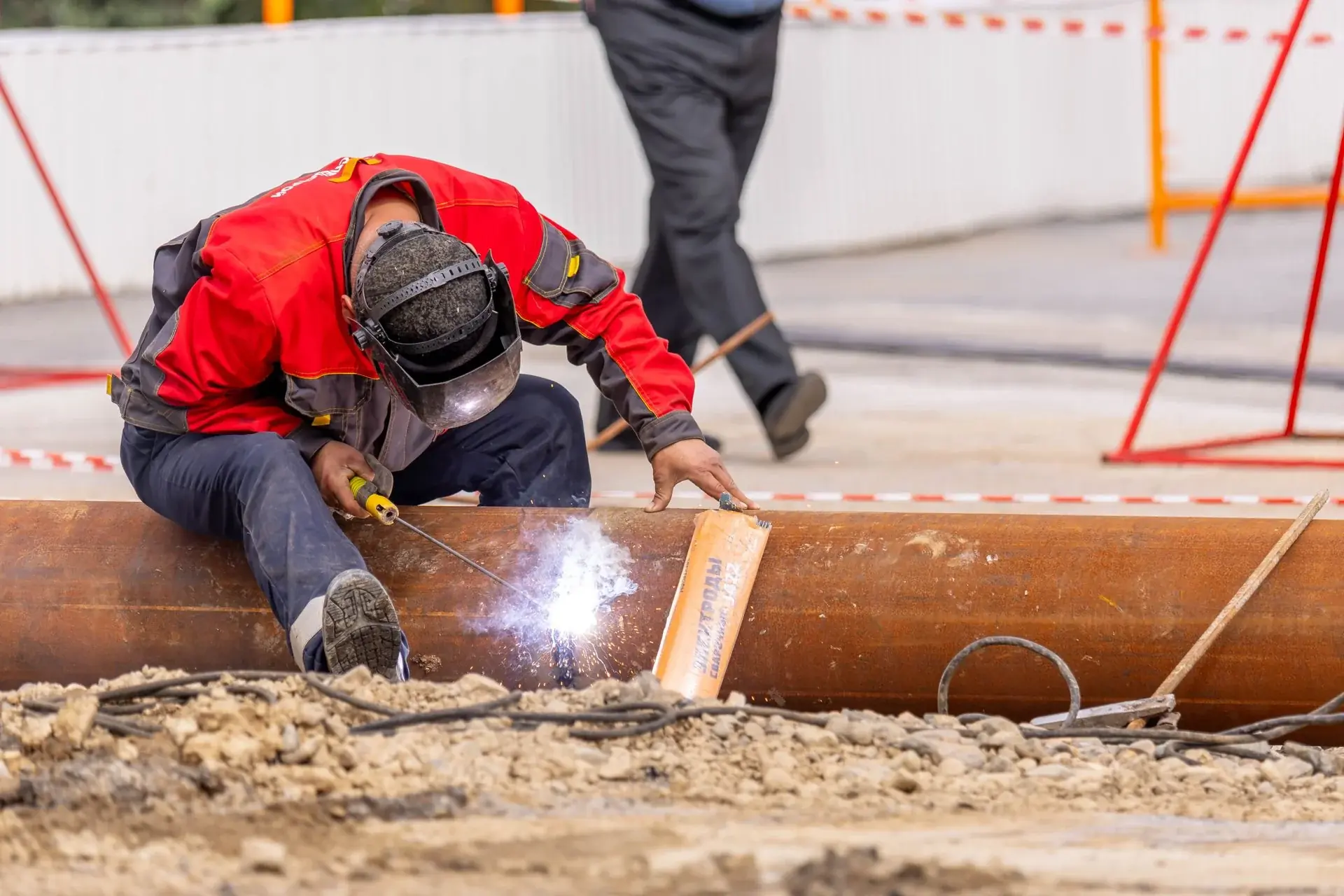Welder working on a steel beam at an active job site