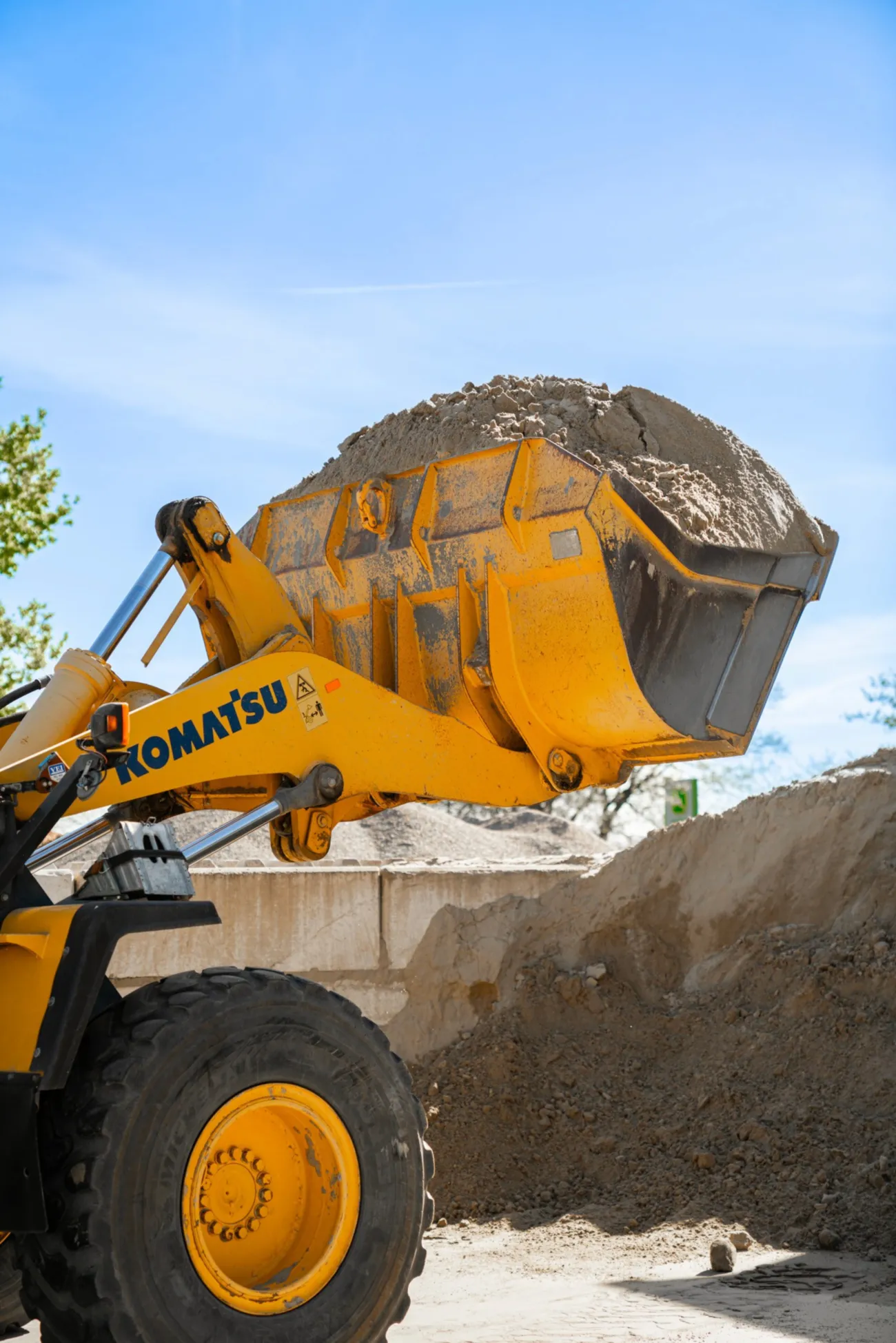 Gelbe Komatsu-Radladerschaufel voller Sand über einem Sandhaufen